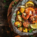 grilled shrimp boil foil packet opened to reveal shrimp, corn, sausage, and potatoes on a rustic wooden table.